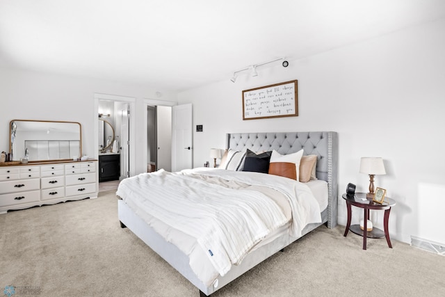 bedroom with light colored carpet and connected bathroom