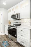 kitchen featuring stainless steel appliances, dark wood-type flooring, and white cabinetry