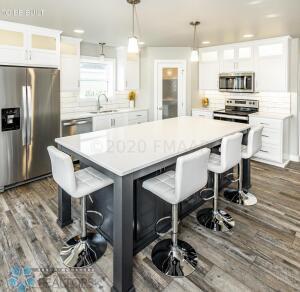 kitchen with a kitchen breakfast bar, a kitchen island, stainless steel appliances, and decorative light fixtures