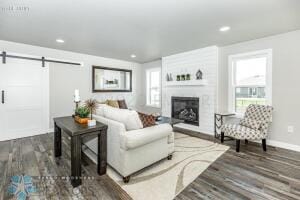 living room featuring a fireplace, dark hardwood / wood-style floors, and a barn door