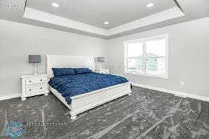 carpeted bedroom with a raised ceiling