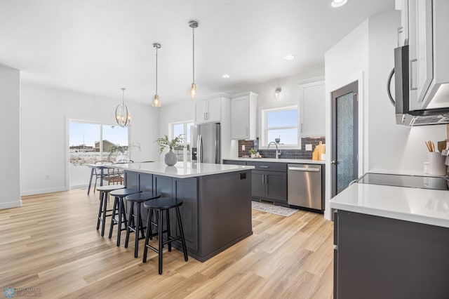 kitchen featuring light wood finished floors, a breakfast bar, a center island, stainless steel appliances, and decorative backsplash