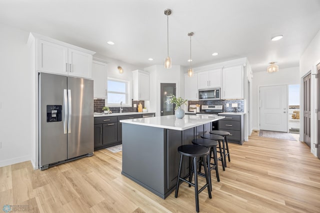 kitchen featuring light countertops, appliances with stainless steel finishes, white cabinetry, a breakfast bar area, and a center island