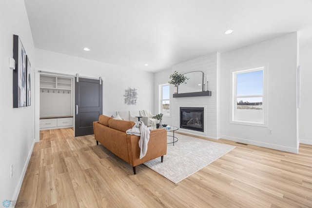 living area featuring light wood finished floors, baseboards, a fireplace, and recessed lighting