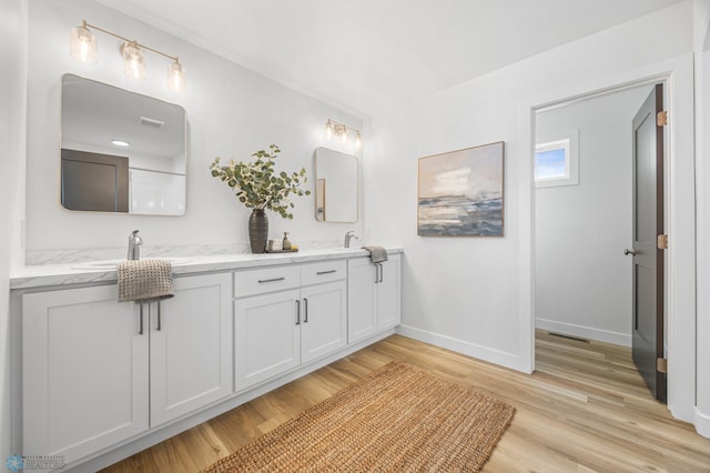 full bathroom with a sink, baseboards, wood finished floors, and double vanity