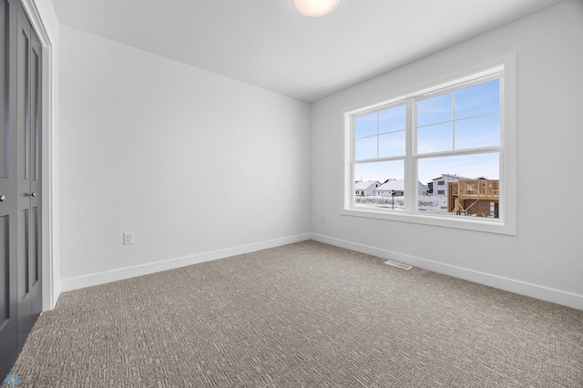 carpeted empty room featuring baseboards and visible vents