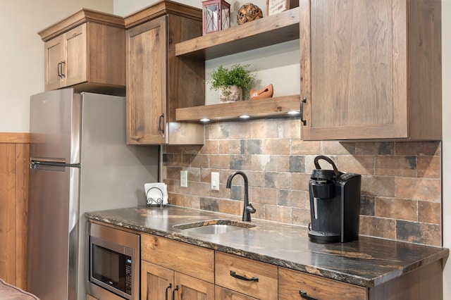 kitchen with sink, appliances with stainless steel finishes, dark stone counters, and decorative backsplash