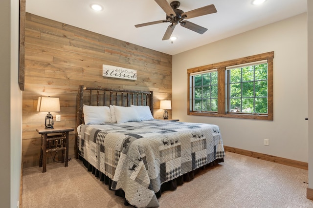 carpeted bedroom featuring wood walls and ceiling fan