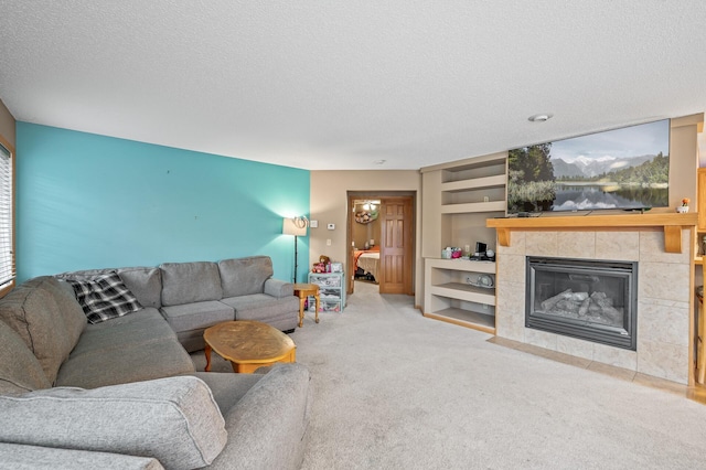 carpeted living room with built in shelves, a textured ceiling, and a tile fireplace