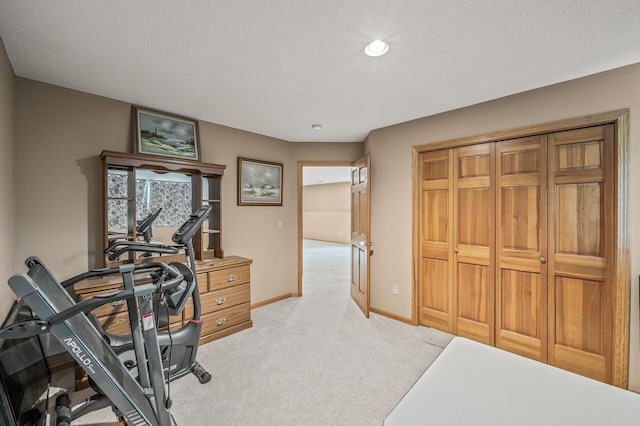 workout area featuring a textured ceiling and light colored carpet