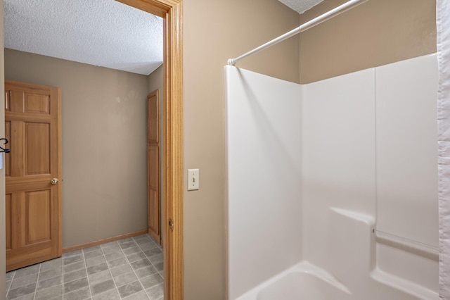 bathroom with a textured ceiling and shower / tub combo