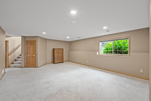 basement featuring light carpet and a textured ceiling