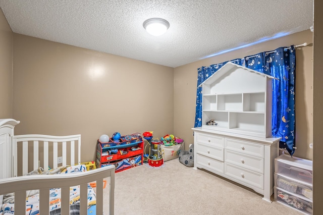 bedroom with a textured ceiling, a crib, and light carpet