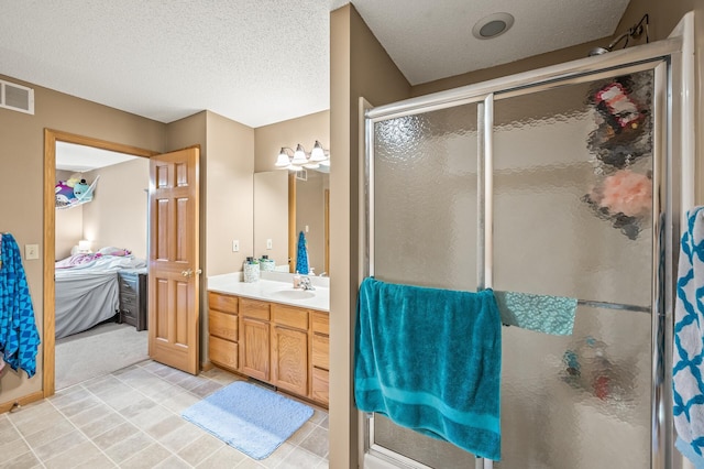 bathroom with vanity, a shower with shower door, and a textured ceiling