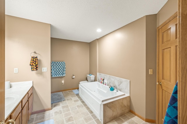 bathroom featuring vanity, a tub to relax in, toilet, and a textured ceiling