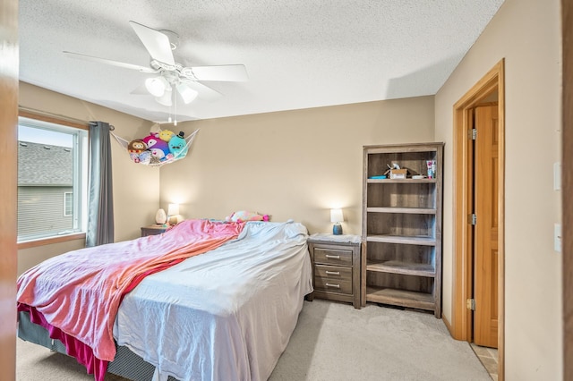 bedroom featuring light carpet, ceiling fan, and a textured ceiling