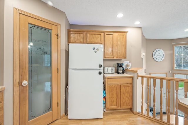 kitchen featuring light hardwood / wood-style flooring, a textured ceiling, and white fridge