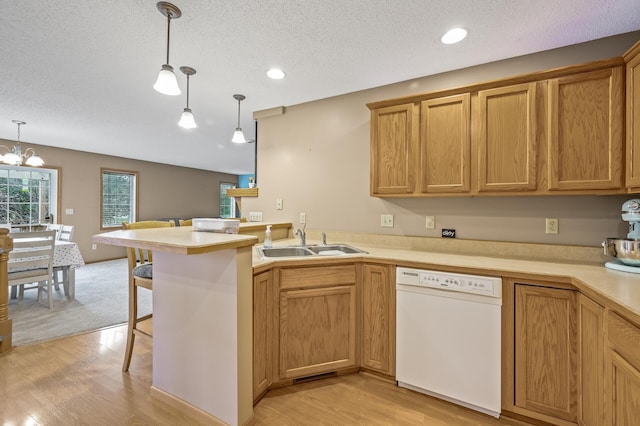 kitchen with dishwasher, sink, a notable chandelier, kitchen peninsula, and hanging light fixtures