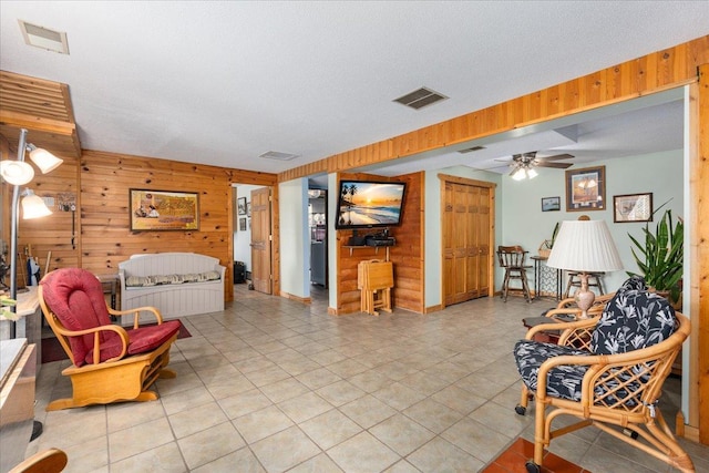 interior space with ceiling fan, wooden walls, and a textured ceiling