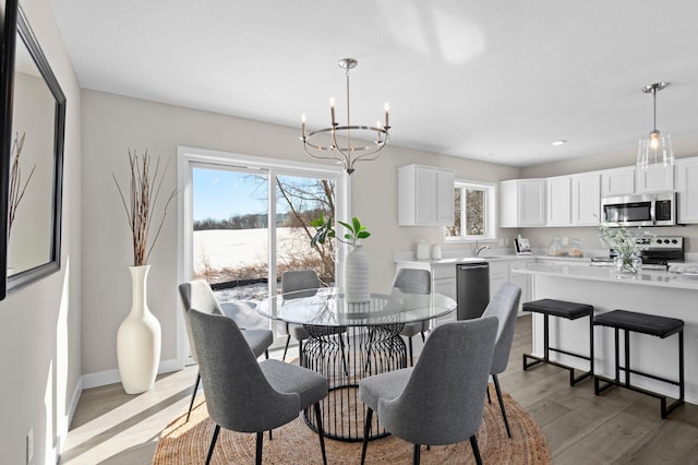 dining space with sink, a chandelier, light hardwood / wood-style floors, and a healthy amount of sunlight