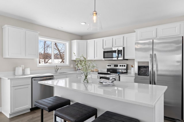 kitchen featuring white cabinets, appliances with stainless steel finishes, a center island, and sink