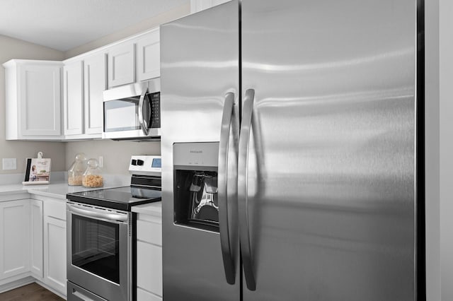 kitchen featuring wood-type flooring, appliances with stainless steel finishes, and white cabinetry