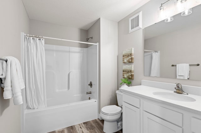 full bathroom featuring a textured ceiling, vanity, shower / tub combo with curtain, wood-type flooring, and toilet