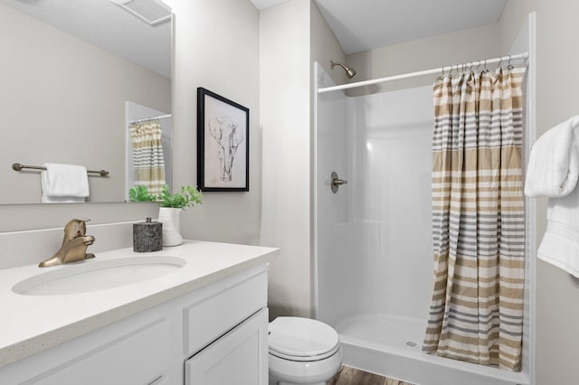 bathroom with hardwood / wood-style floors, walk in shower, toilet, and vanity