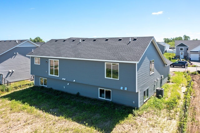 rear view of property featuring a yard and central air condition unit