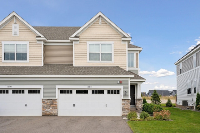 view of front of home with a garage, a front lawn, and central air condition unit