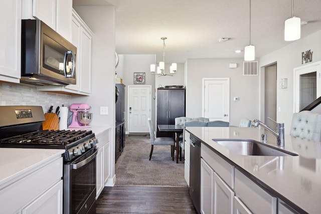 kitchen with sink, white cabinetry, stainless steel appliances, and hanging light fixtures