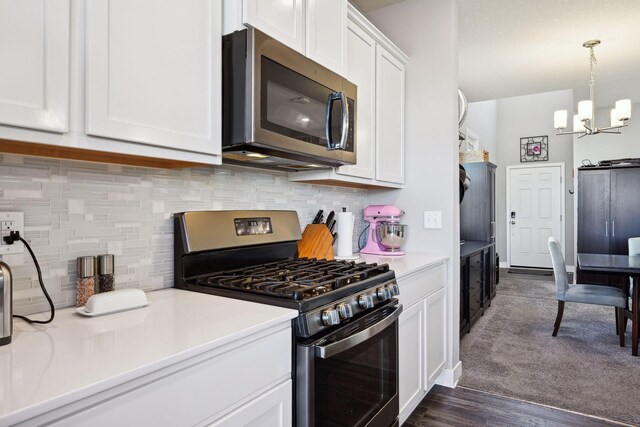 kitchen with hanging light fixtures, appliances with stainless steel finishes, tasteful backsplash, a notable chandelier, and white cabinetry