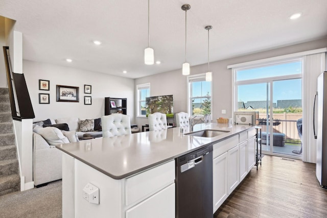 kitchen featuring white cabinets, sink, an island with sink, decorative light fixtures, and stainless steel appliances