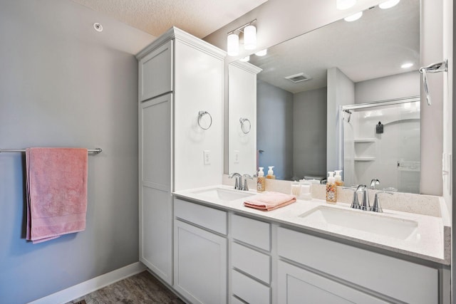 bathroom with a textured ceiling, hardwood / wood-style floors, vanity, and an enclosed shower