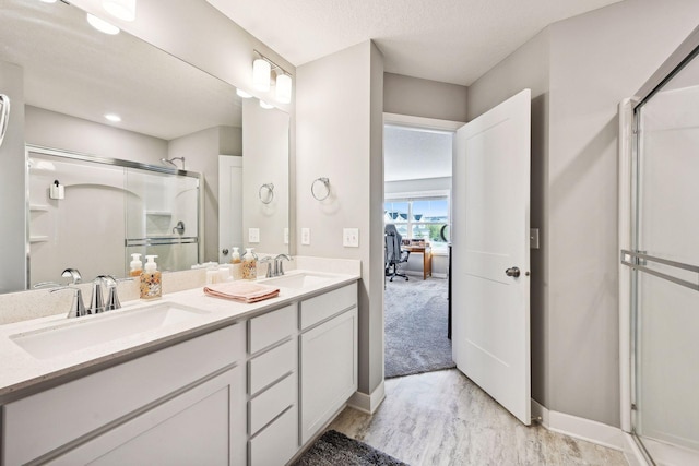 bathroom with a textured ceiling, vanity, and walk in shower