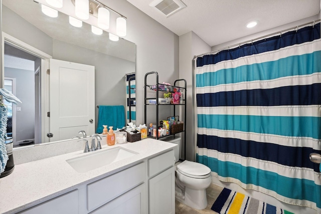 bathroom with a shower with curtain, vanity, toilet, and a textured ceiling