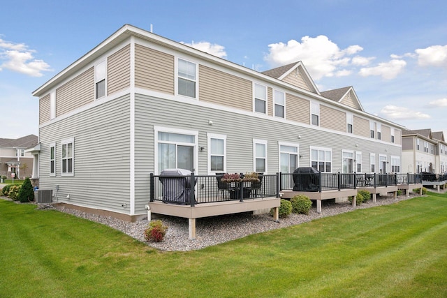 rear view of property with a deck, a yard, and central AC