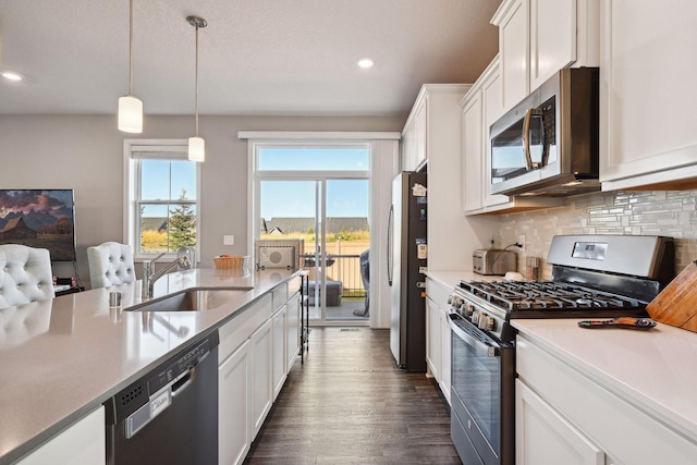 kitchen with appliances with stainless steel finishes, tasteful backsplash, sink, decorative light fixtures, and white cabinets