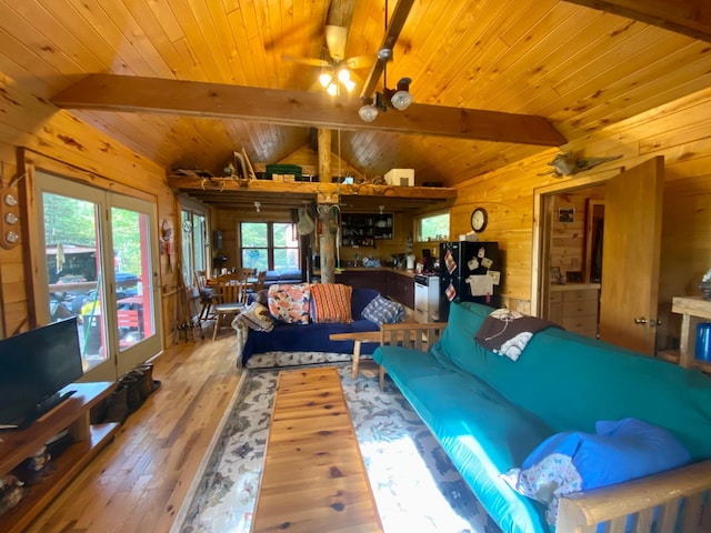 living room featuring a wealth of natural light, hardwood / wood-style floors, wooden walls, and lofted ceiling with beams