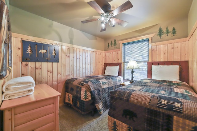 carpeted bedroom featuring wood walls and ceiling fan