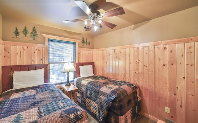 bedroom with ceiling fan and wooden walls