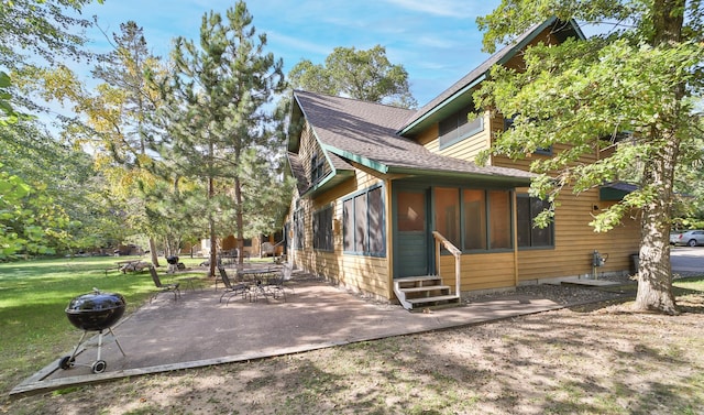 view of side of property featuring a sunroom, a yard, and a patio