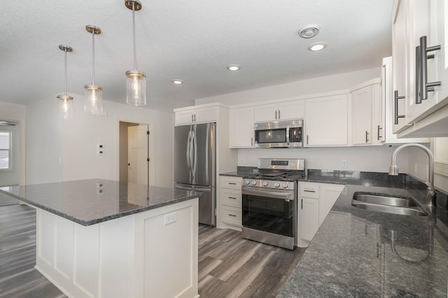 kitchen featuring white cabinets, dark wood-type flooring, sink, appliances with stainless steel finishes, and decorative light fixtures