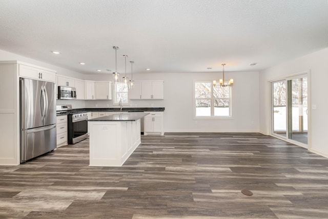 kitchen featuring stainless steel appliances, decorative light fixtures, and a healthy amount of sunlight