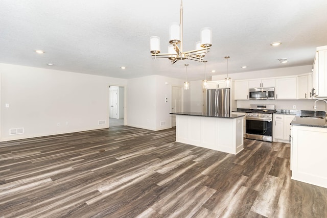 kitchen with hanging light fixtures, white cabinetry, stainless steel appliances, dark hardwood / wood-style floors, and a center island