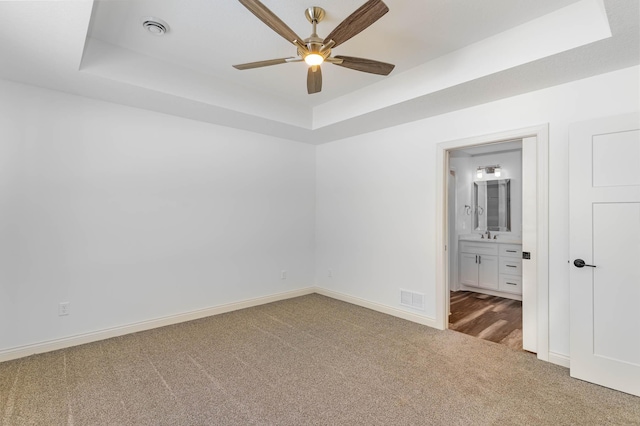 unfurnished room featuring ceiling fan, a tray ceiling, and carpet flooring