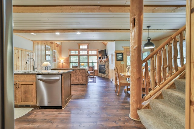 kitchen featuring a fireplace, sink, light stone countertops, dark hardwood / wood-style floors, and stainless steel dishwasher