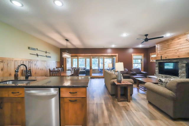 kitchen featuring dishwasher, brown cabinets, open floor plan, and a sink