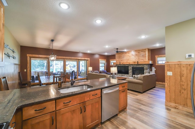 kitchen with a fireplace, sink, ceiling fan, hanging light fixtures, and stainless steel dishwasher