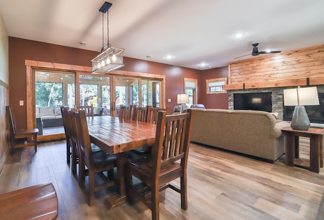 dining space with light wood-type flooring, ceiling fan, a fireplace, and french doors